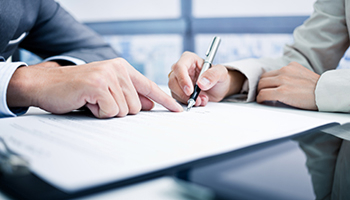 Close-up of a legal professional's hands pointing at a document while explaining it to a client.